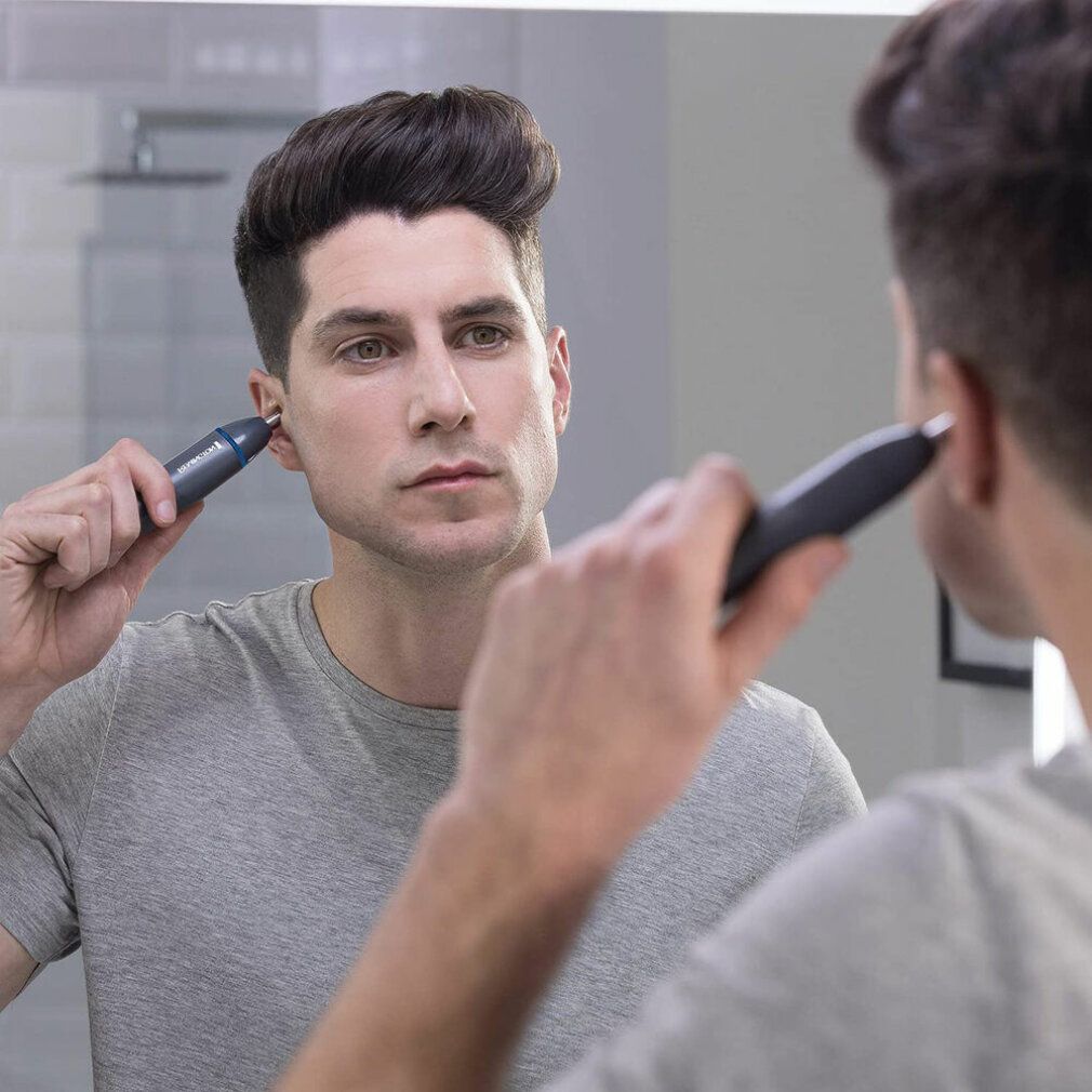 Uomo usa un trimmer naso/orecchie davanti a uno specchio. Il prodotto è nero.