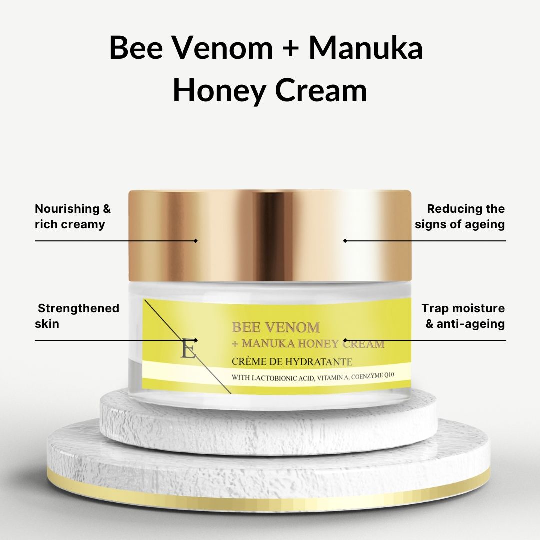 Vasetto di crema con coperchio dorato. Etichetta gialla con testo: Bee Venom + Manuka Honey Cream. Su piedistallo.