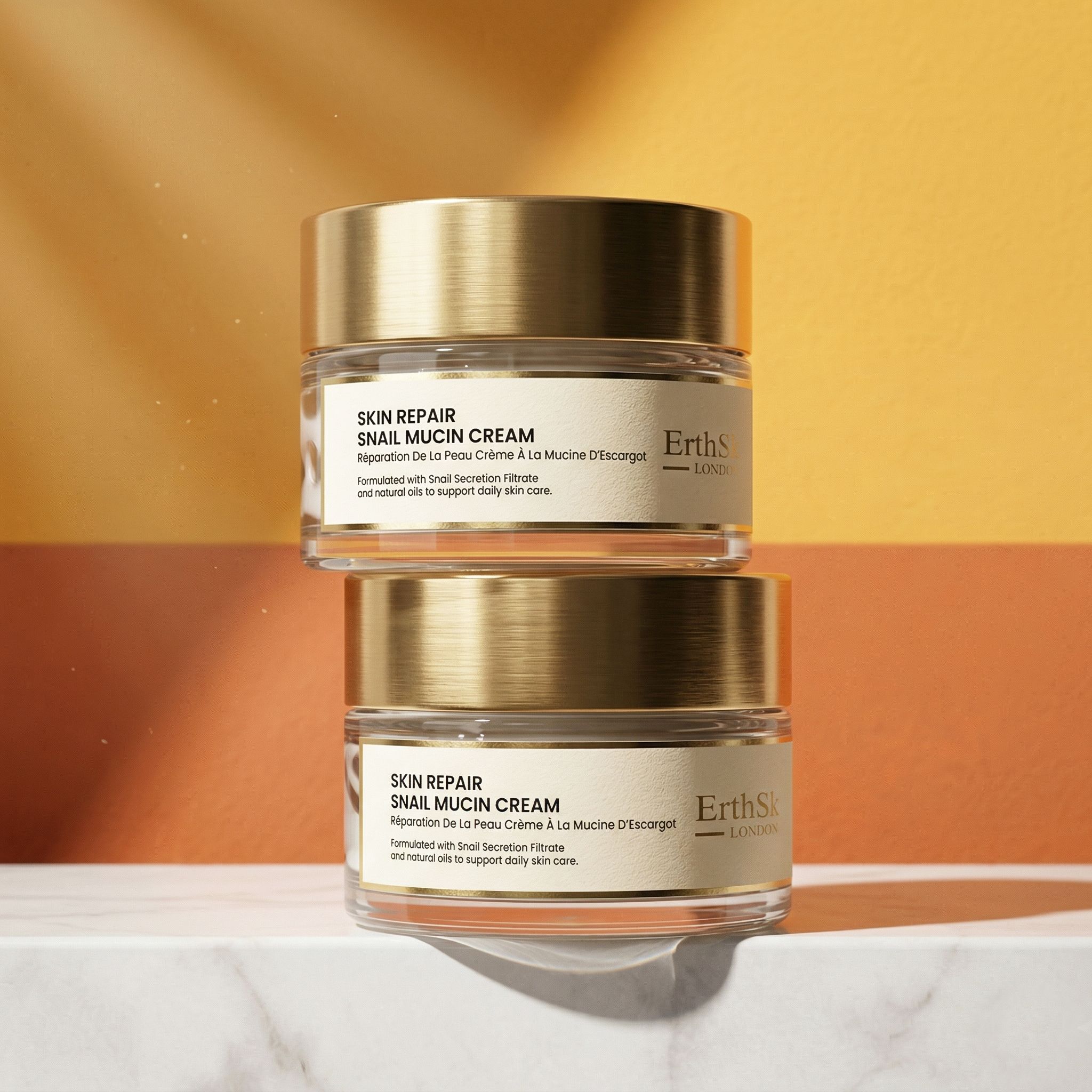 Due vasetti di vetro con coperchi dorati. Scritta: Skin Repair Snail Mucin Cream. Marchio: ErthSkin London.