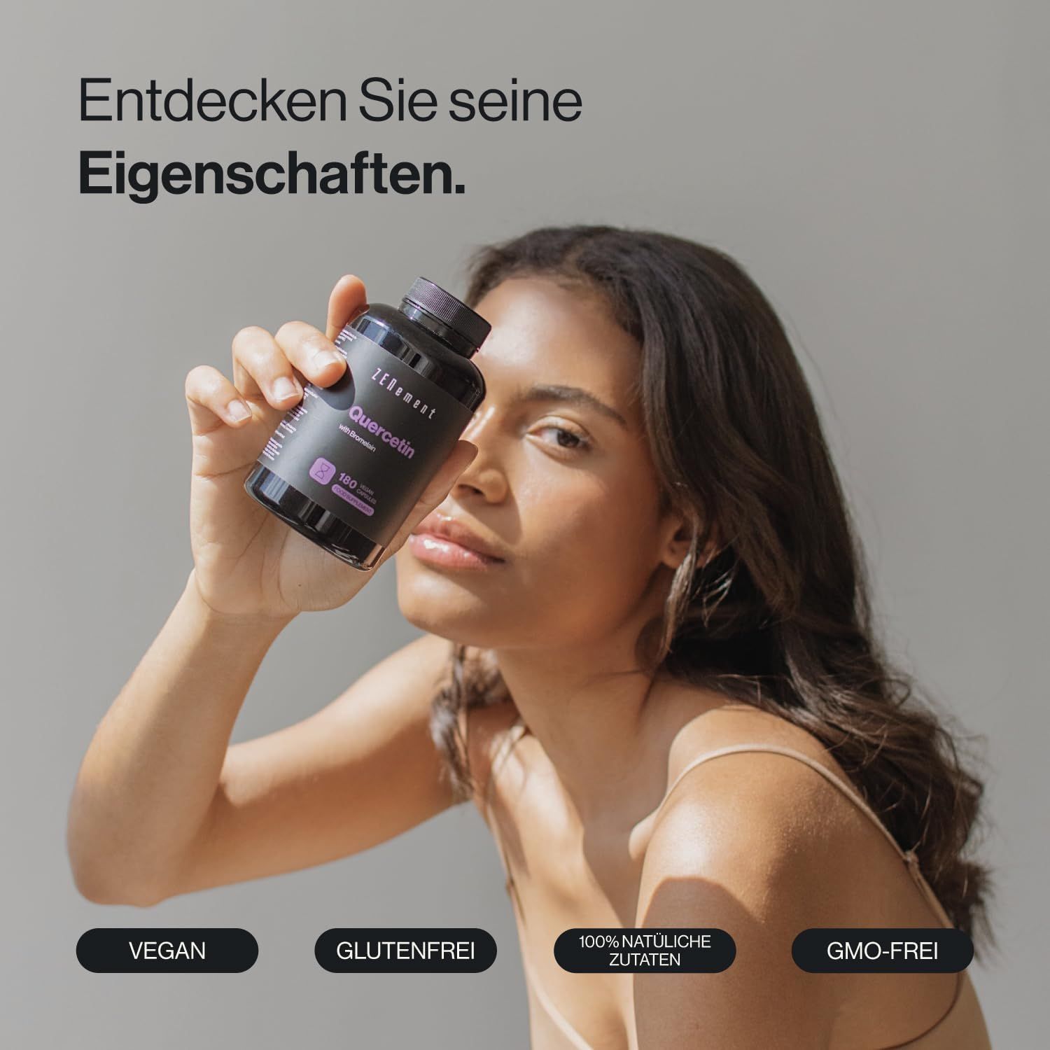 Donna tiene in mano una bottiglia di capsule di quercetina Zenement. Scritte: Vegano, Senza glutine, 100% ingredienti naturali, Non OGM.