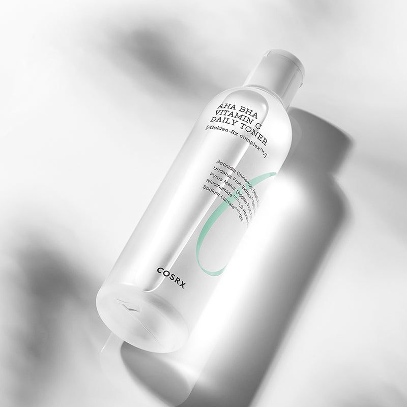 Flacone trasparente inclinato con tappo bianco. Scritta: AHA BHA Vitamin C Daily Toner. Marchio: COSRX.