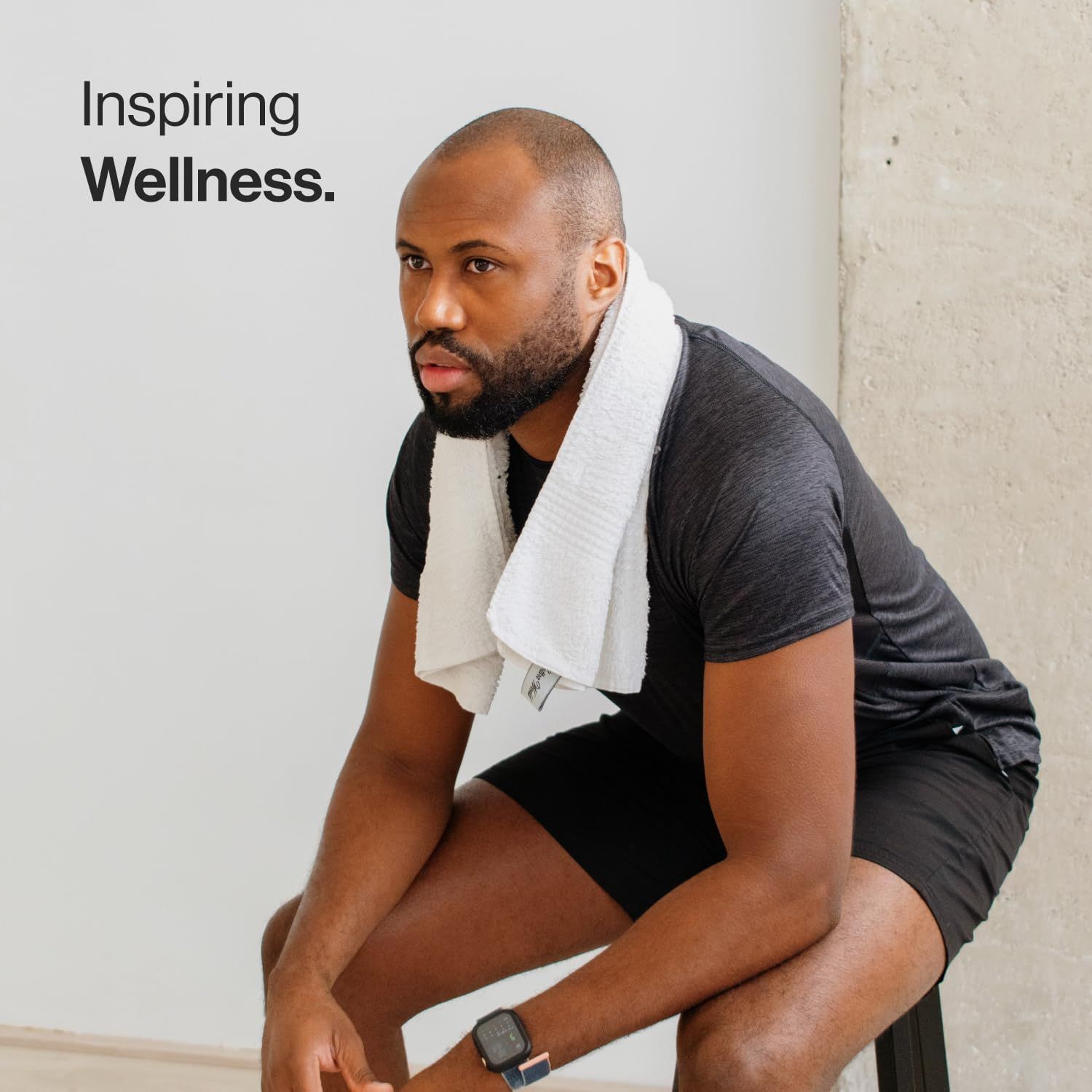 Un uomo seduto con un asciugamano al collo. Indossa abiti sportivi.