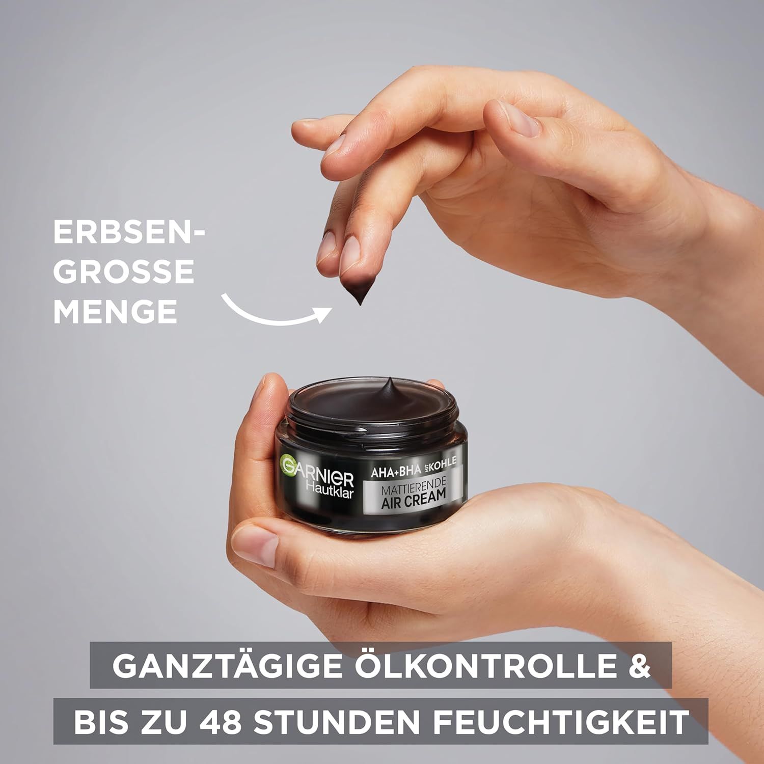 Mani che tengono un vasetto di crema Garnier Hautklar AHA+BHA Kohle Air Cream. Freccia indica la quantità di crema.