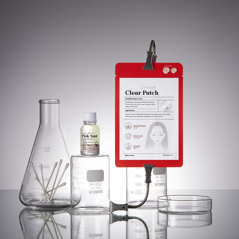 Confezione rossa con etichetta del prodotto. Materiale da laboratorio: becher, provette, pipette, flacone. Nome prodotto: Clear Patch.