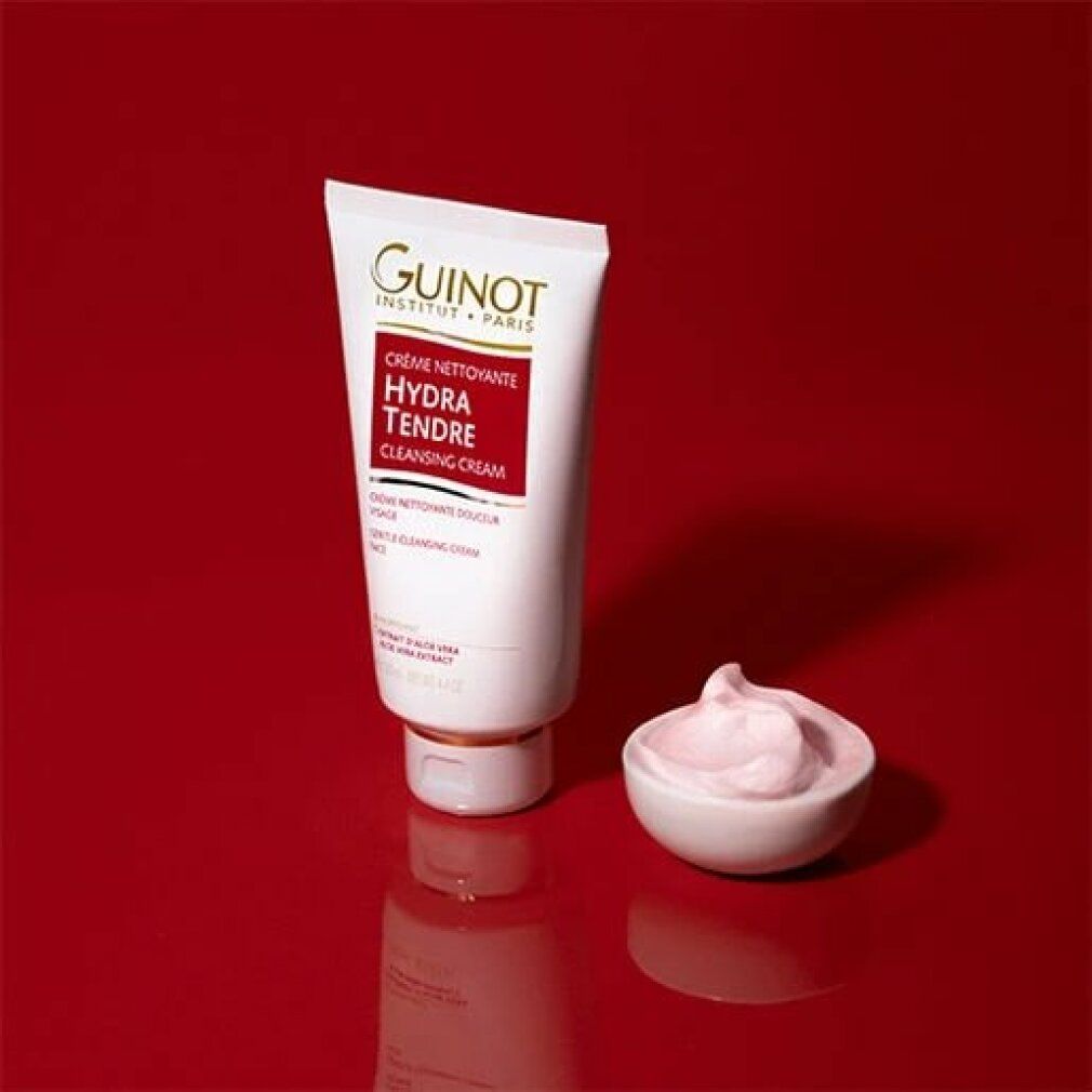 Tubo bianco e ciotola con crema rosa su sfondo rosso. Logo Guinot e Hydra Tendre. Testo: Cleansing Cream.