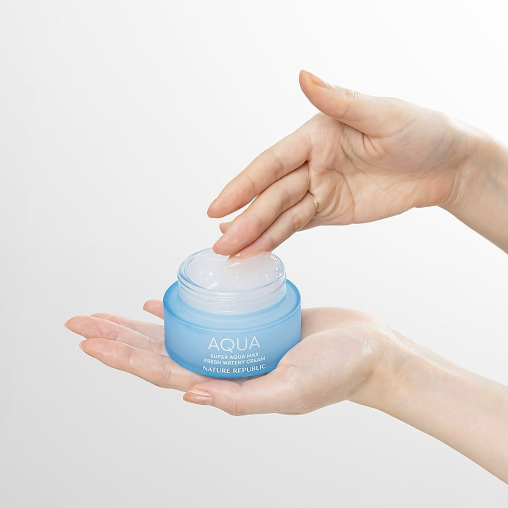 Mani che tengono un vasetto blu aperto. Scritta: AQUA, SUPER AQUA MAX FRESH WATERY CREAM, NATURE REPUBLIC. Crema visibile.