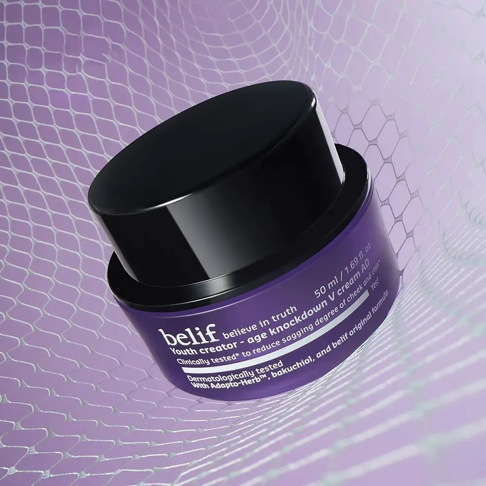 Vaso viola con coperchio nero. Testo: belif, Youth creator - age knockdown V cream AD. 50 ml. Su rete bianca.