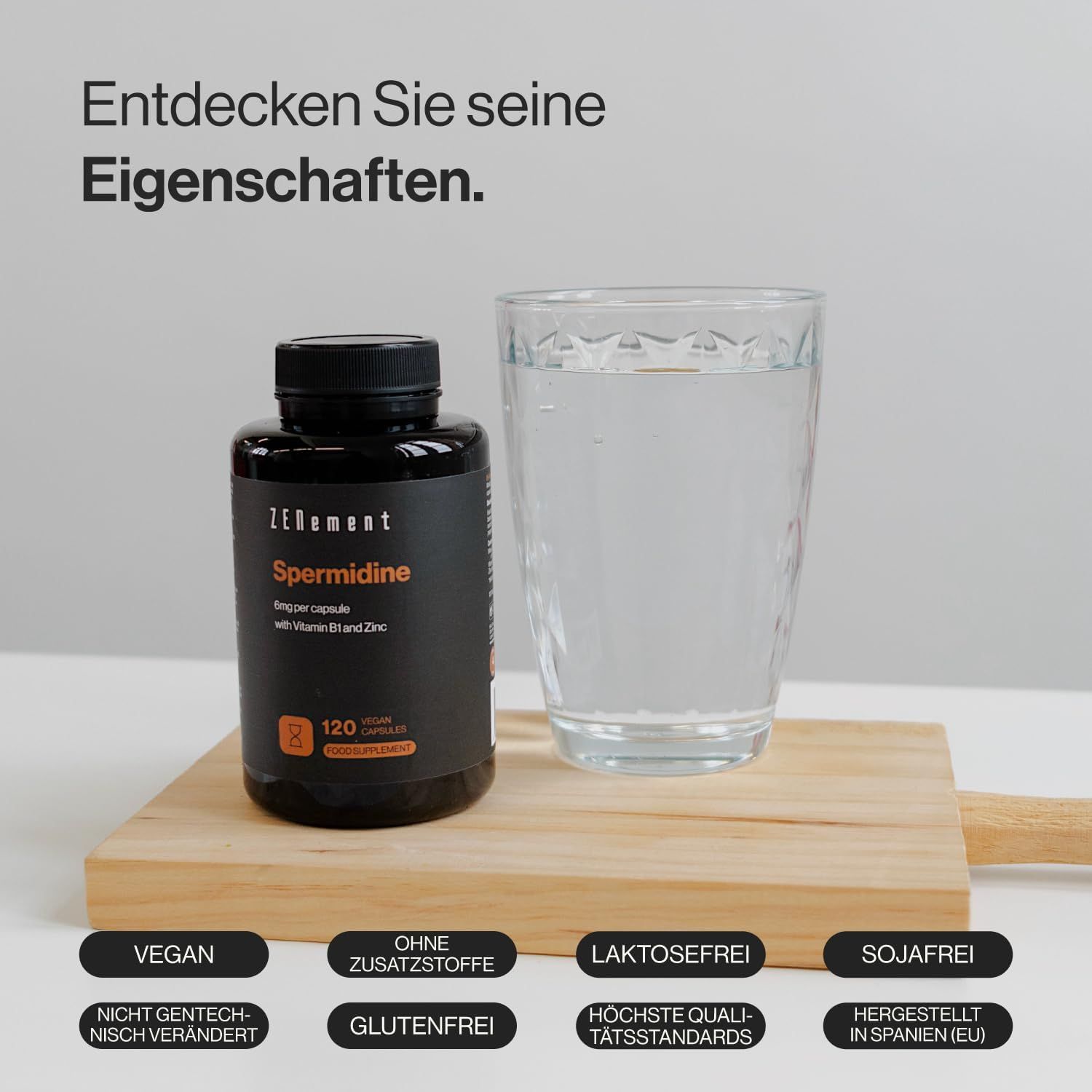 Flacone nero di capsule di spermidina, bicchiere d'acqua, tagliere in legno. Vegano, senza additivi, senza lattosio, senza soia, senza OGM.