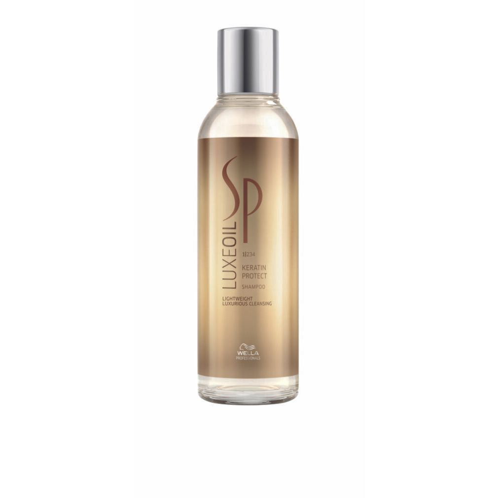 Flacone trasparente di shampoo dorato. Etichetta SP Luxe Oil, Keratin Protect Shampoo. Tappo argentato.