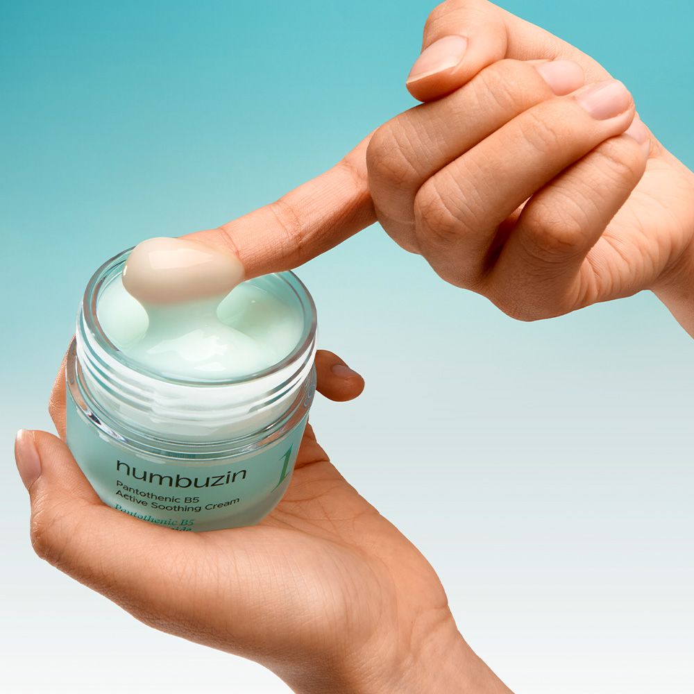 Una mano preleva la crema Numbuzin Pantothenic B5 da un barattolo con un dito.