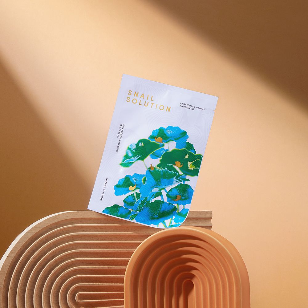 Maschera in tessuto bianca con design floreale. Posizionata su archi marroni. Testo: Snail Solution.