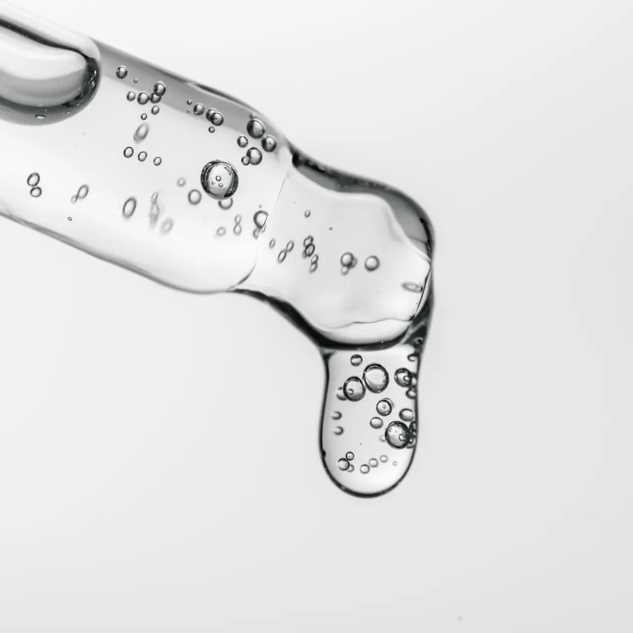 Primo piano di una pipetta con siero. Liquido trasparente con bolle. Formazione di gocce.