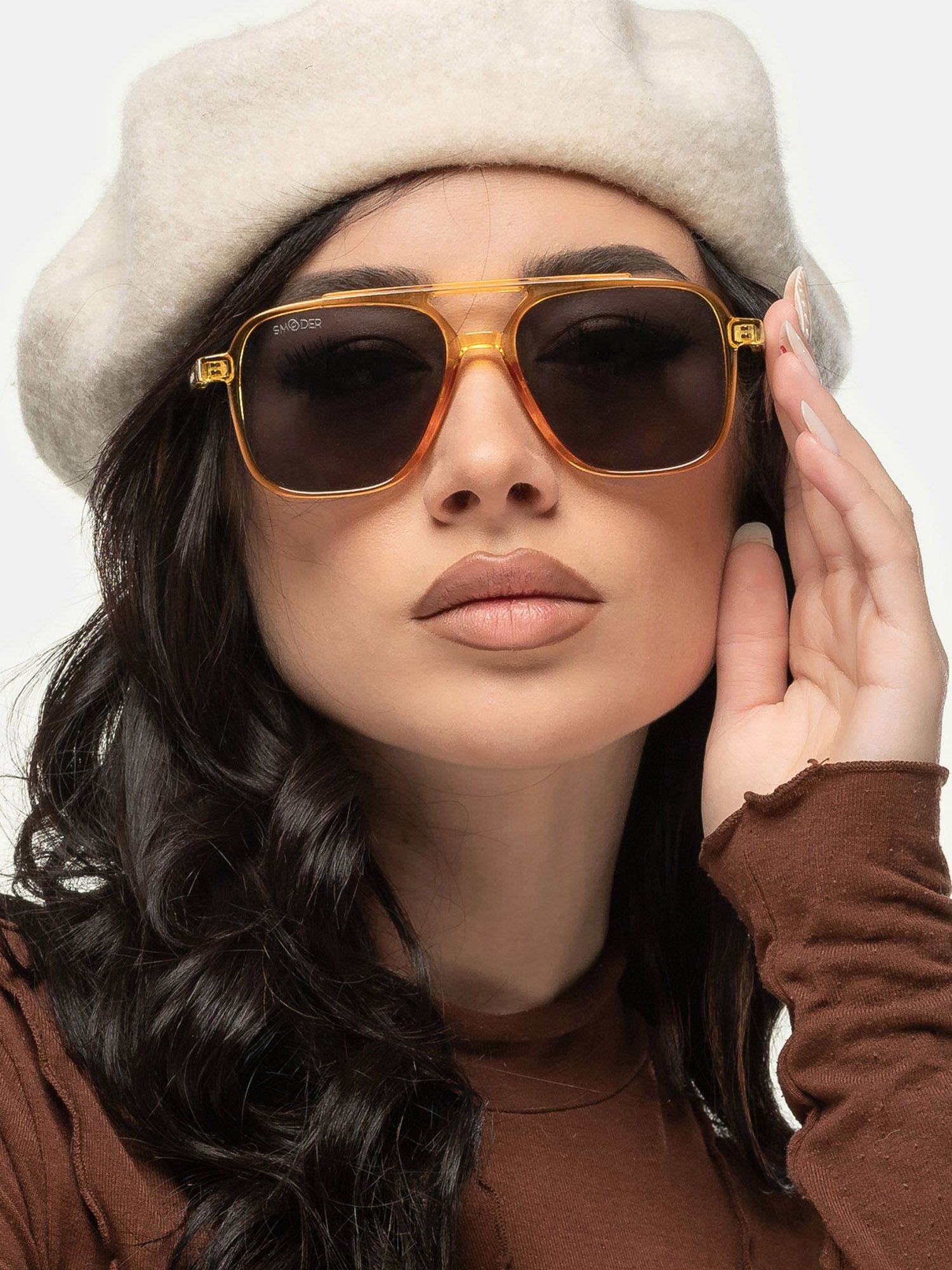 Donna con occhiali da sole arancioni e lenti scure. Marchio Smooder. Indossa un cappello.