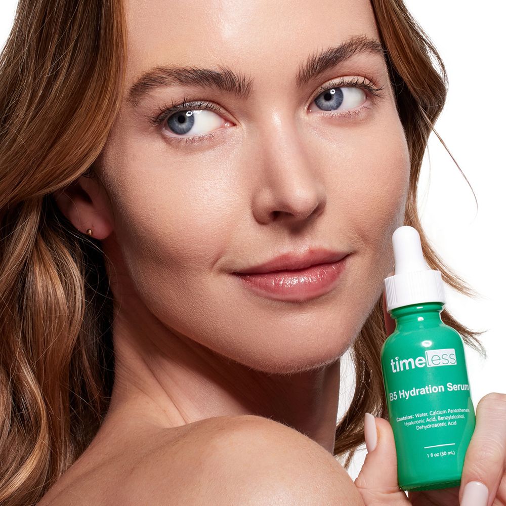 Donna tiene in mano un flacone verde. Scritta: timeless, B5 Hydration Serum. Viso in primo piano. Prodotto per la cura della pelle.