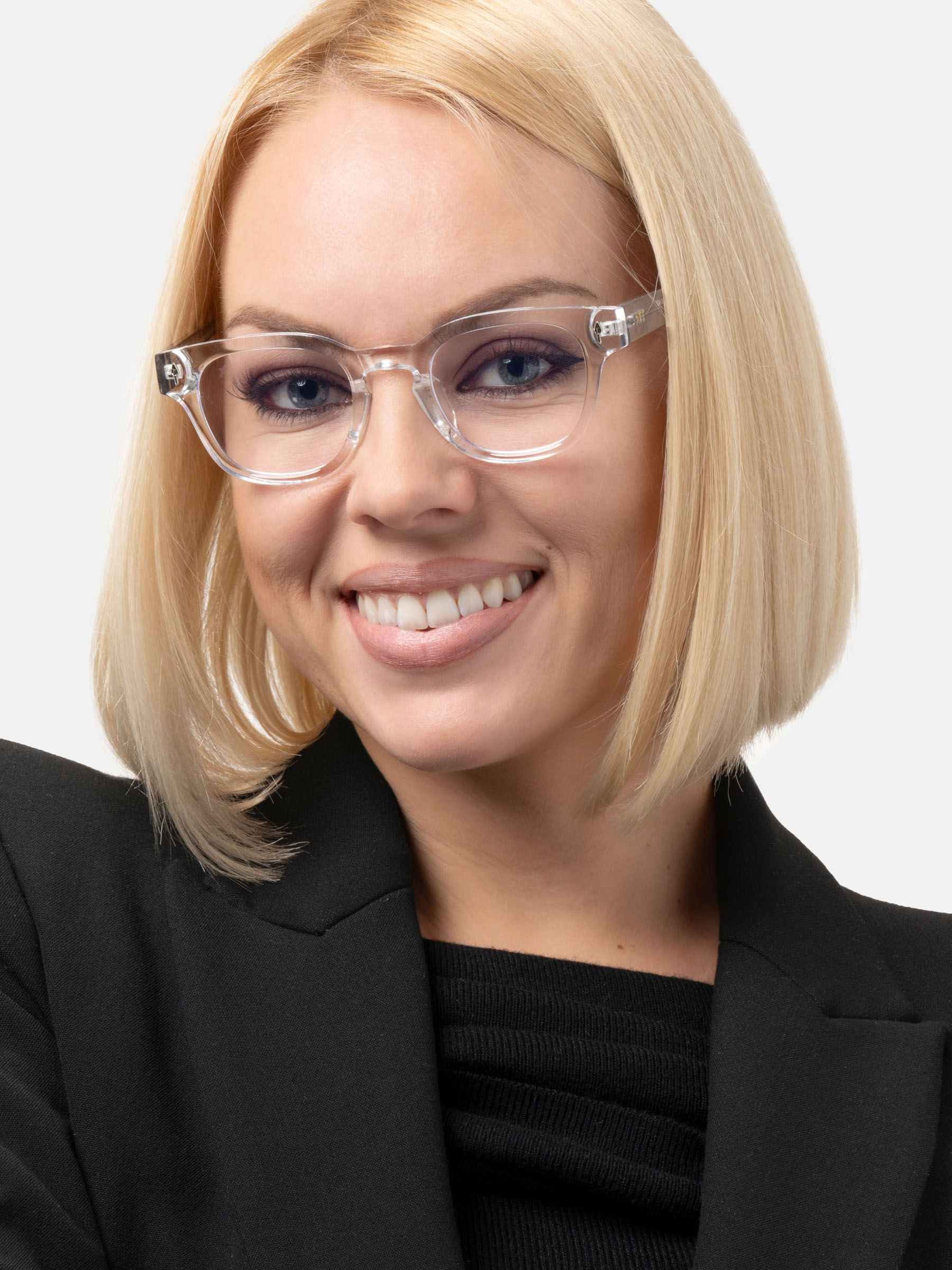 Donna bionda con occhiali trasparenti. Blazer nero. Gli occhiali hanno lenti rotonde e montatura trasparente.