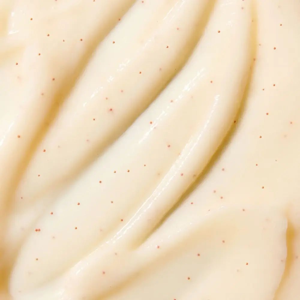 Primo piano di crema bianca cremosa con piccole particelle rosse. Texture liscia.