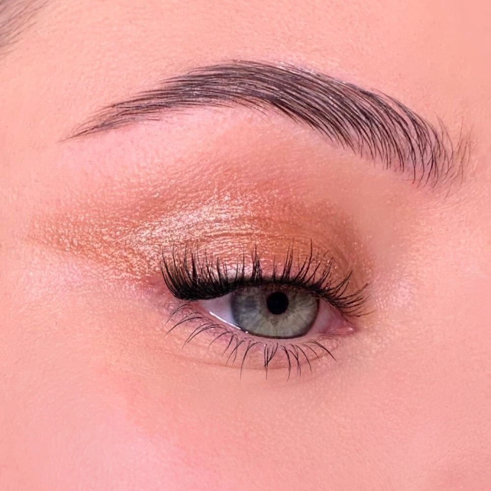 Occhio truccato. Ombretto dorato sulla palpebra. Ciglia allungate.