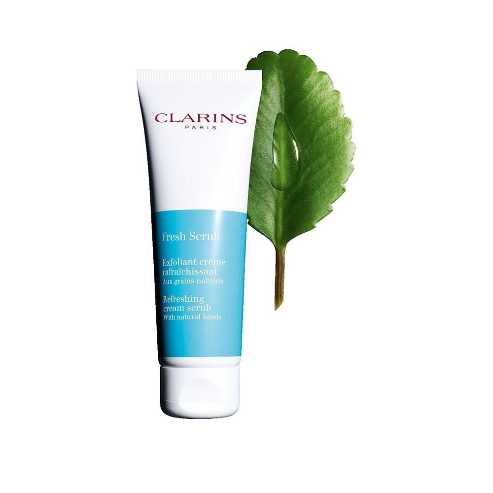 Tubo bianco con sezione blu, Clarins Paris. Fresh Scrub. Accanto, una foglia verde con una goccia d'acqua.