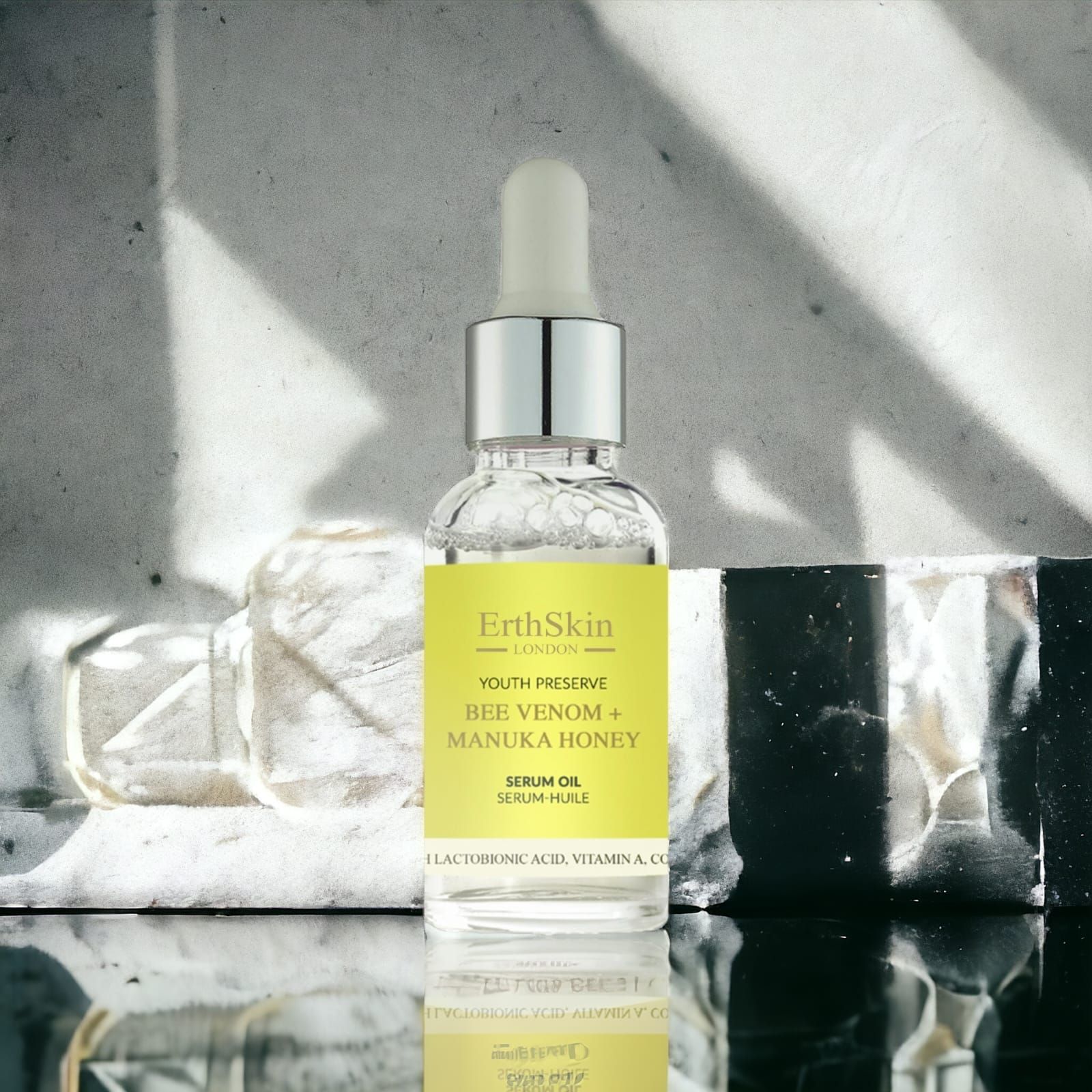 Flacone di siero ErthSkin London con etichetta gialla. Contiene veleno d'api e miele di Manuka. Con pipetta. Su una superficie.
