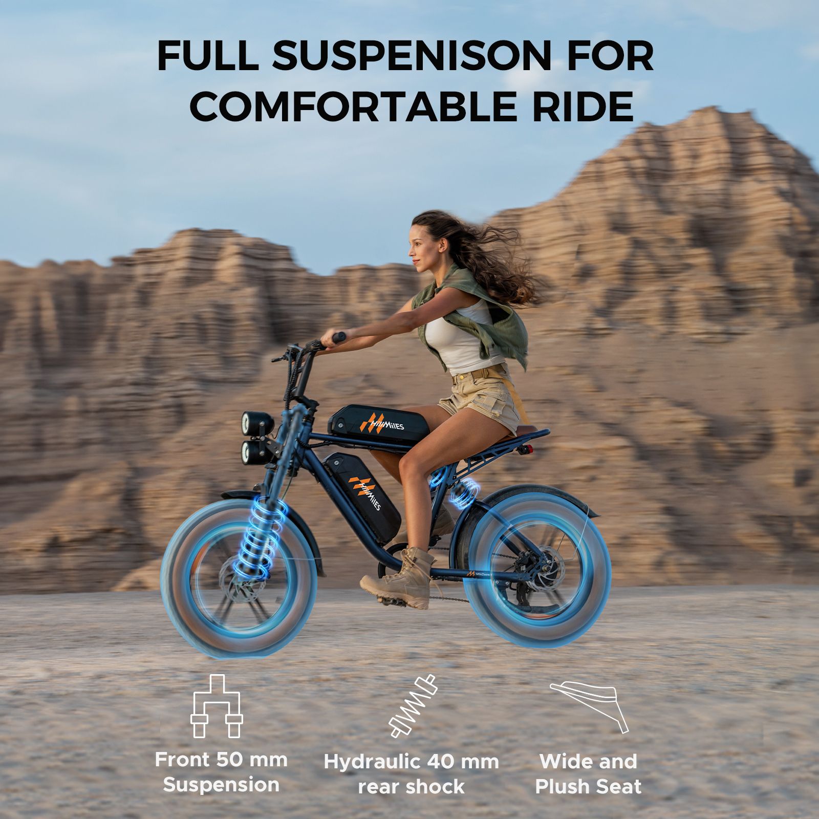 E-bike blu. Donna in sella. Testo: Full Suspension for Comfortable Ride. Sospensione anteriore 50 mm, ammortizzatore posteriore idraulico 40 mm, sella ampia.