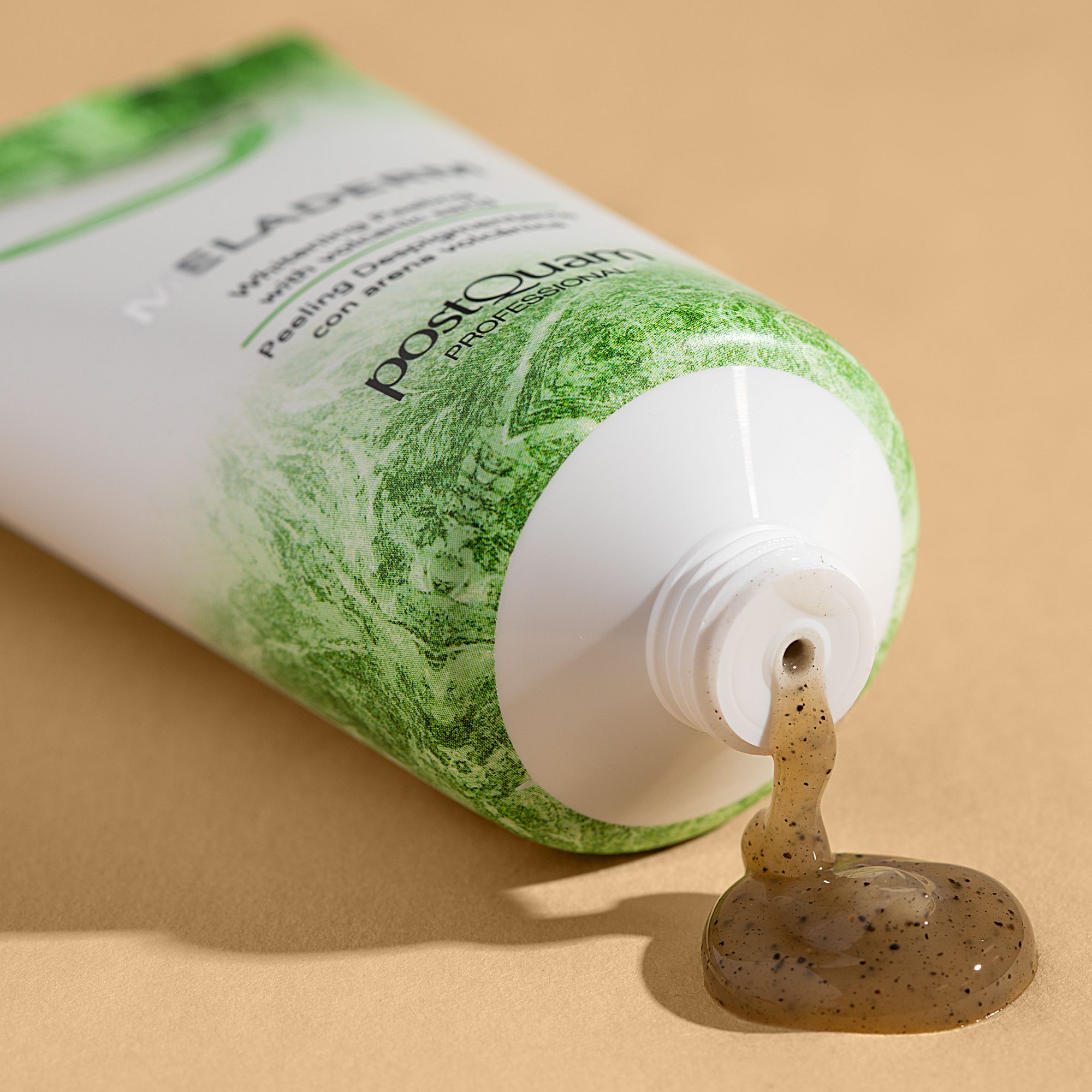 Tubo bianco, stampa verde. Prodotto che esce dall'apertura. Testo: MELADERM, Whitening Peeling with volcanic sand, postQuam PROFESSIONAL.
