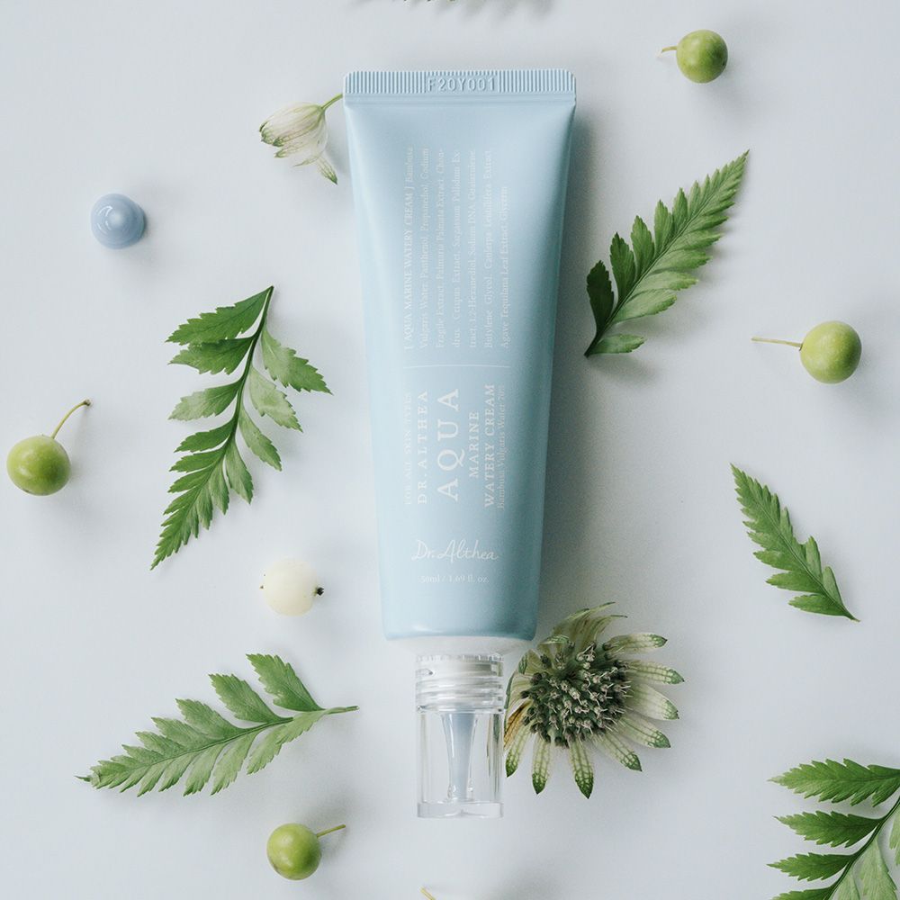 Tubo azzurro circondato da foglie e frutta. Scritta: Aqua Marine Watery Cream.
