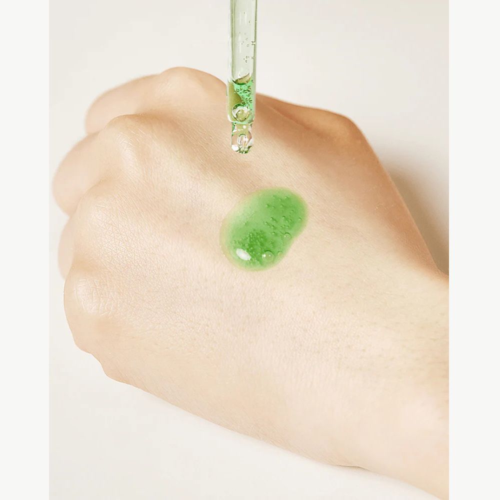 Mano con goccia di siero verde. Siero sulla pelle. Pipetta sopra.