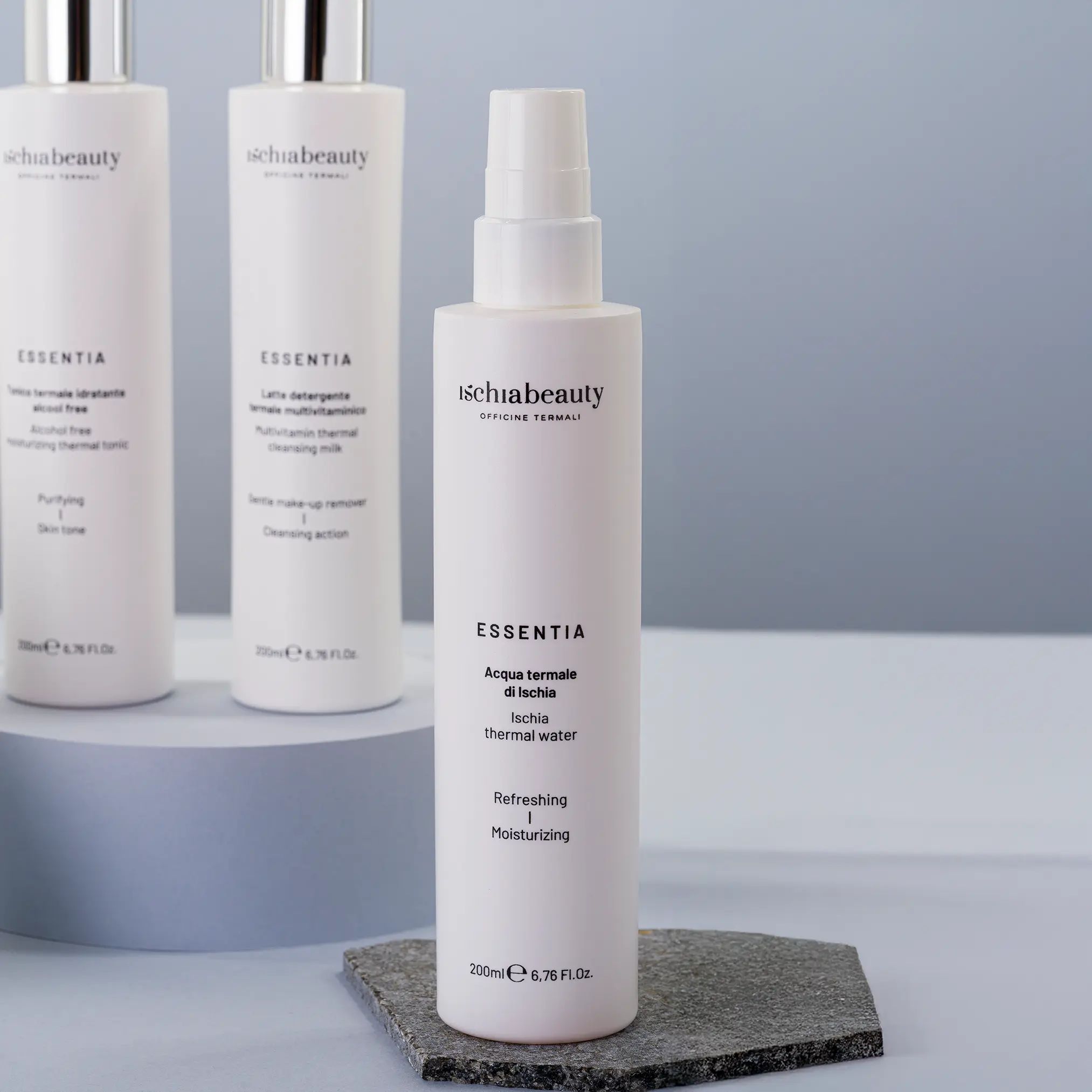 Tre spray bianchi con 'ischiabeauty' e 'ESSENTIA'. 'Acqua termale di Ischia'. Posizionati su una pietra.