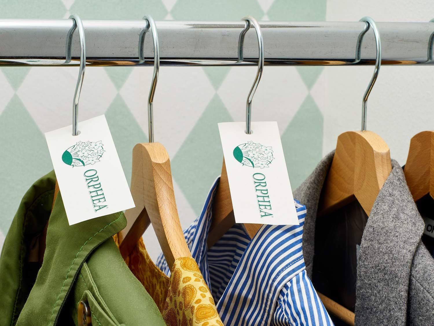 Etichette ORPHEA su grucce. Abiti di vari colori appesi.