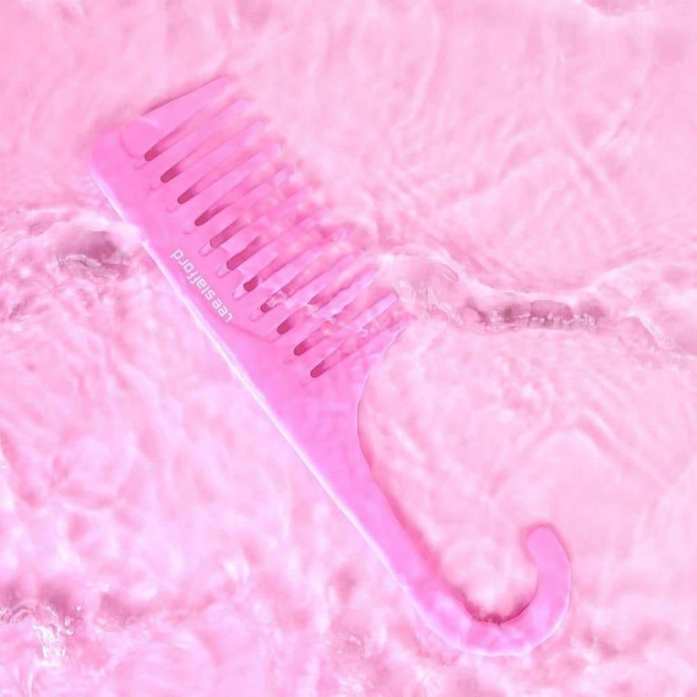 Un pettine rosa a denti larghi galleggia in acqua leggermente mossa.