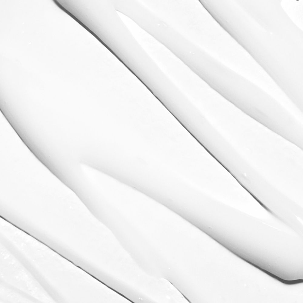 Primo piano di crema bianca applicata in linee ondulate. La consistenza è liscia e lucida.