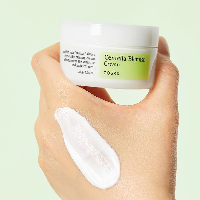 Mano con crema sul dito. Scritta: Centella Blemish Cream, COSRX. Etichetta verde e bianca. Testo: 30 g / 1,05 OZ.
