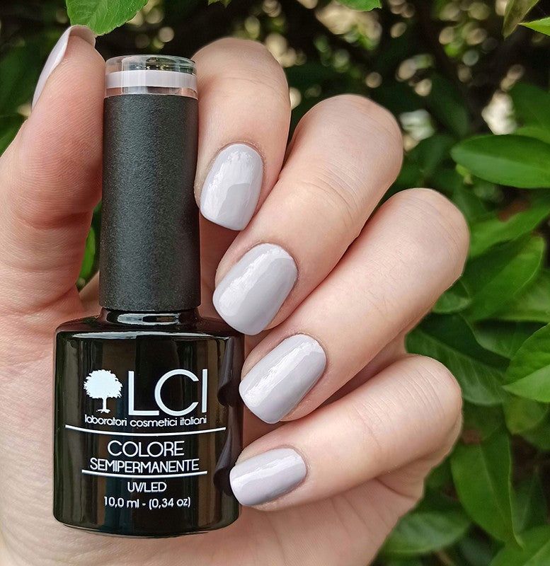 Flacone di smalto e unghie laccate grigio chiaro. Scritta: LCI, Colore Semipermanente, UVLED.