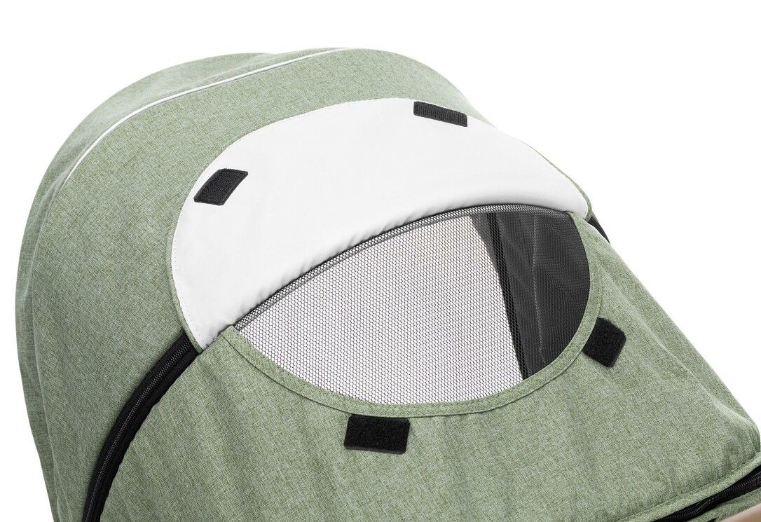 Primo piano della cappottina di un passeggino. Visiera bianca, finestra a rete, tessuto verde.
