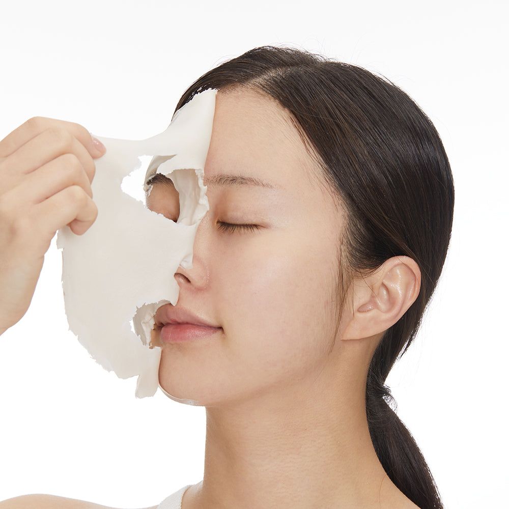 Una donna applica una maschera facciale che copre metà del suo viso.