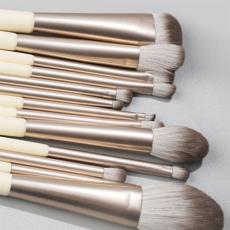 Primo piano di pennelli per trucco. Manici color crema, ghiera argentata e diverse testine.