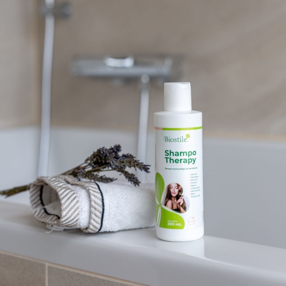 Flacone Biostile Shampoo Therapy vicino ad asciugamano e lavanda. Contesto bagno.