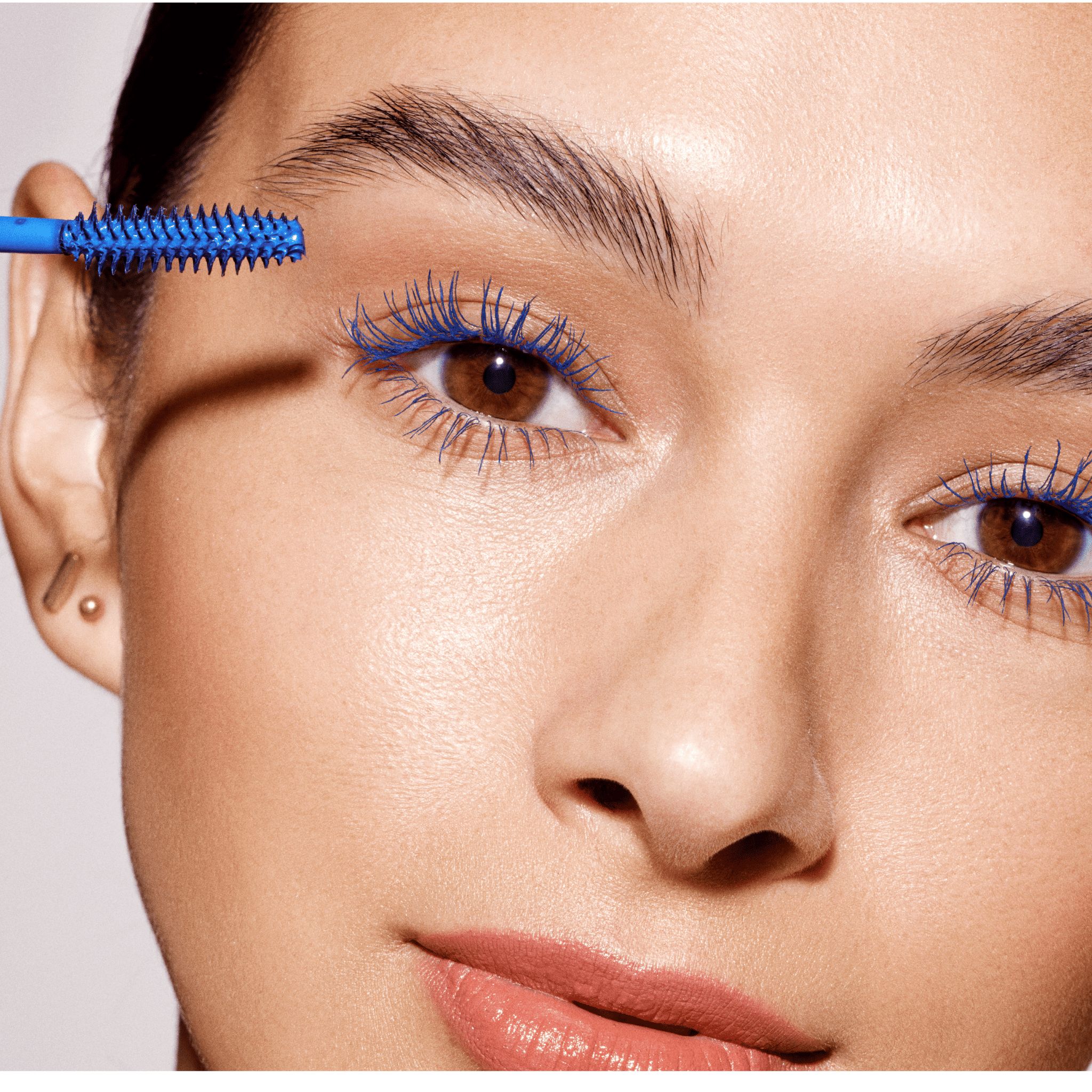 Una donna applica mascara blu con il pennello blu del Double-Ended Volume Set.