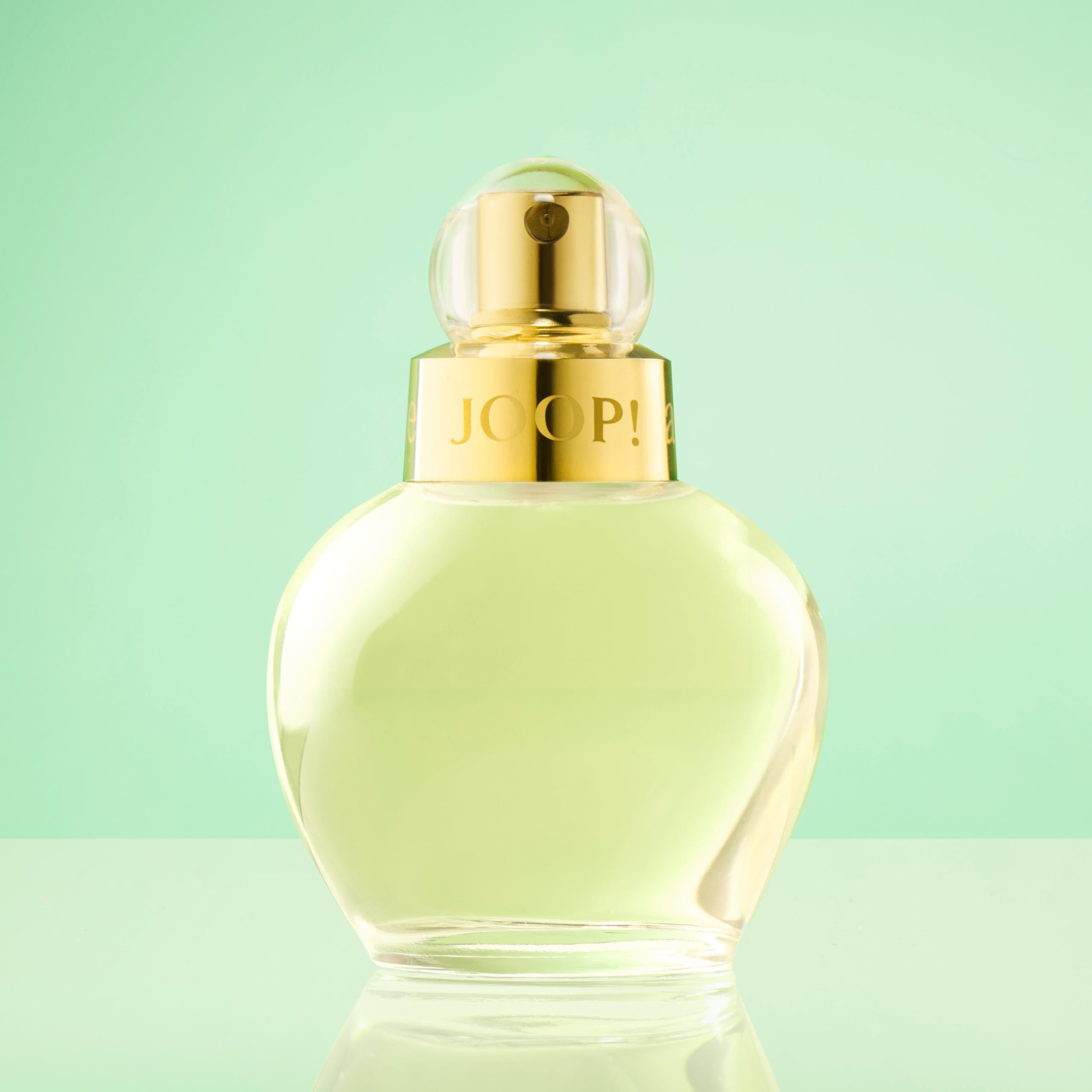 Flacone Joop! All About Eve Edp Spray. Flacone rotondo, tappo dorato. Su sfondo verde.