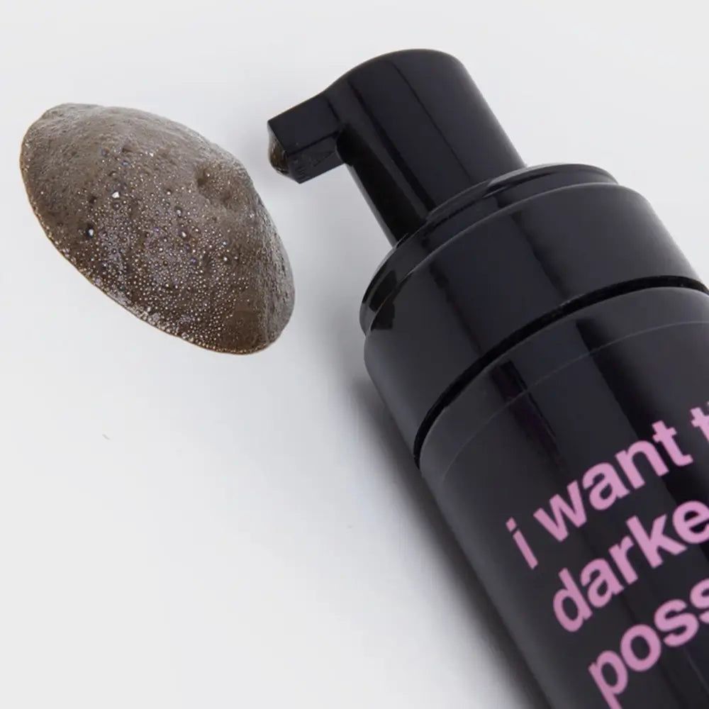 Flacone nero con pompa e campione di mousse abbronzante. Scritta "I want the darkest tan possible".