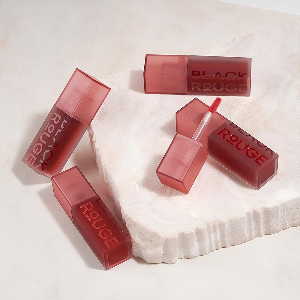 Diversi contenitori di lucidalabbra, parzialmente aperti, con la scritta BLACK ROUGE.