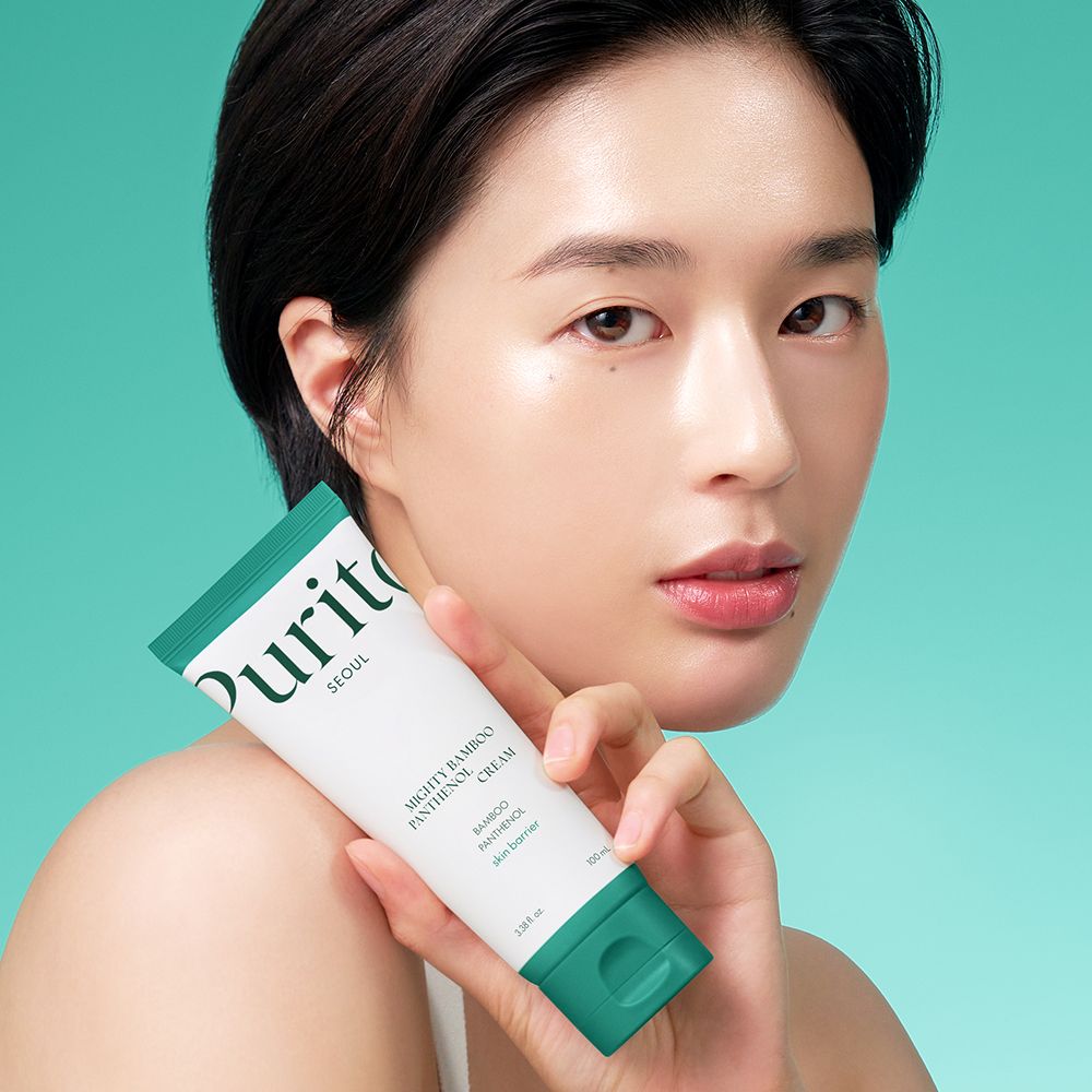 Una donna tiene in mano un tubo di Purito Mighty Bamboo Panthenol Cream.