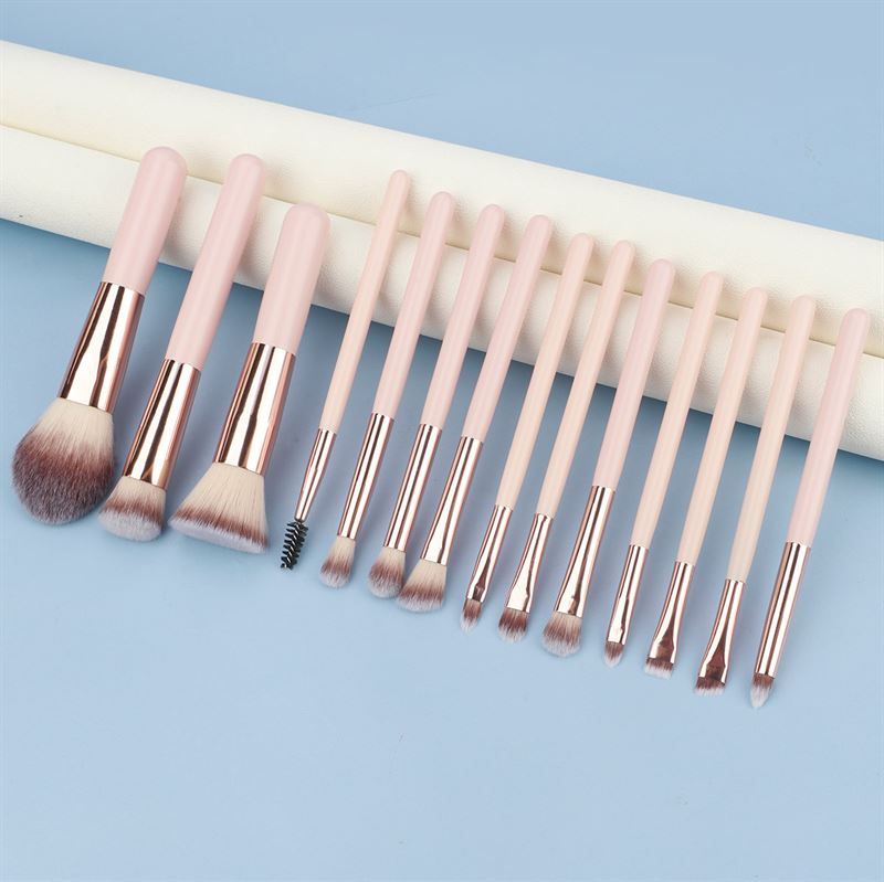 Set di pennelli per trucco. Manici rosa, ghiera dorata, diverse testine. Su sfondo blu.