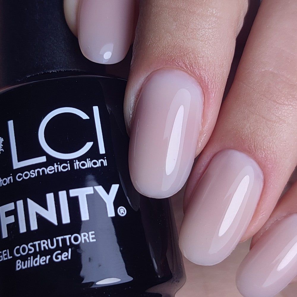 Mano con unghie smaltate. Gel costruttore LCI Cosmetics Infinity sul flacone. Gel rosa chiaro applicato sulle unghie.