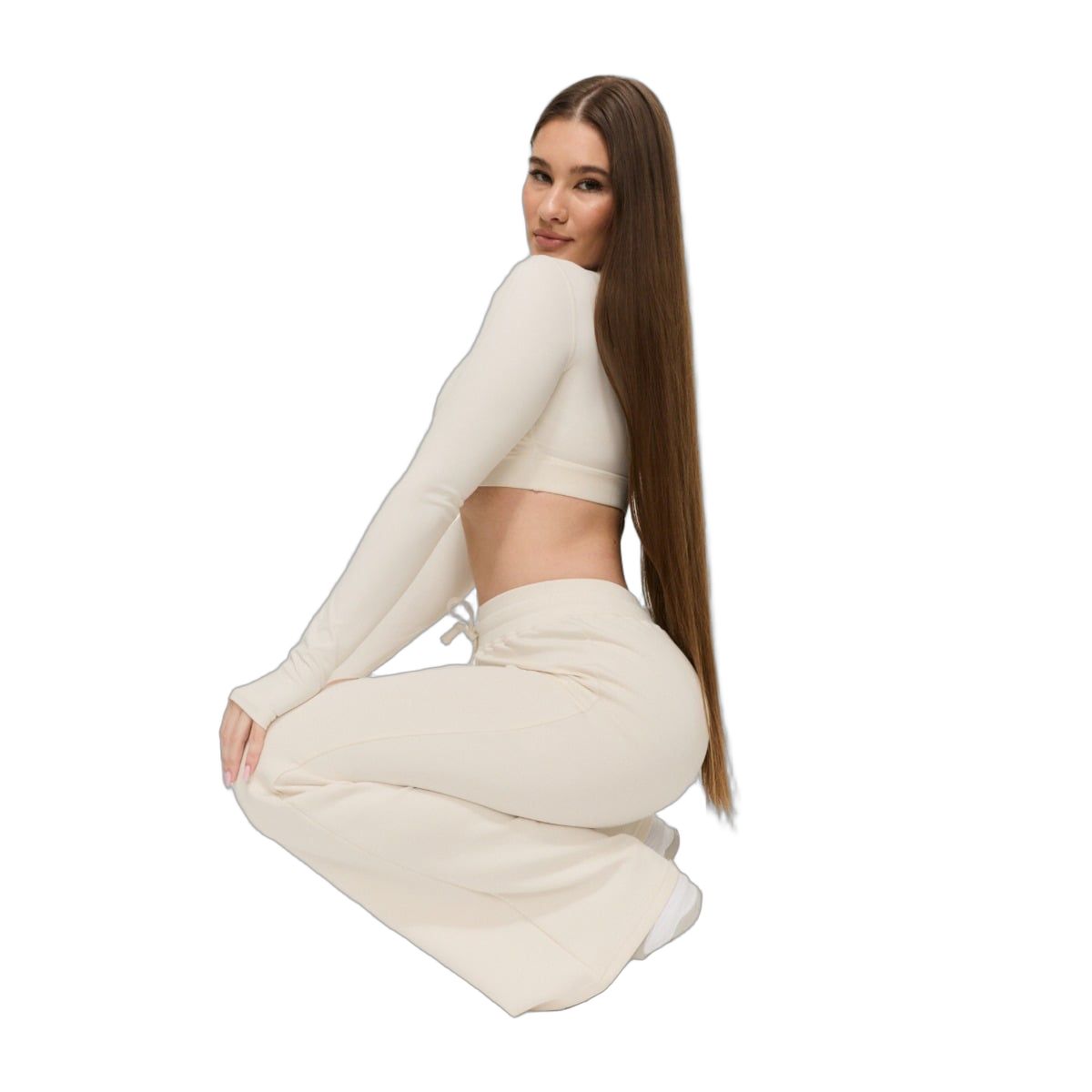 Donna con pantaloni da jogging color crema a gamba larga e top a maniche lunghe.