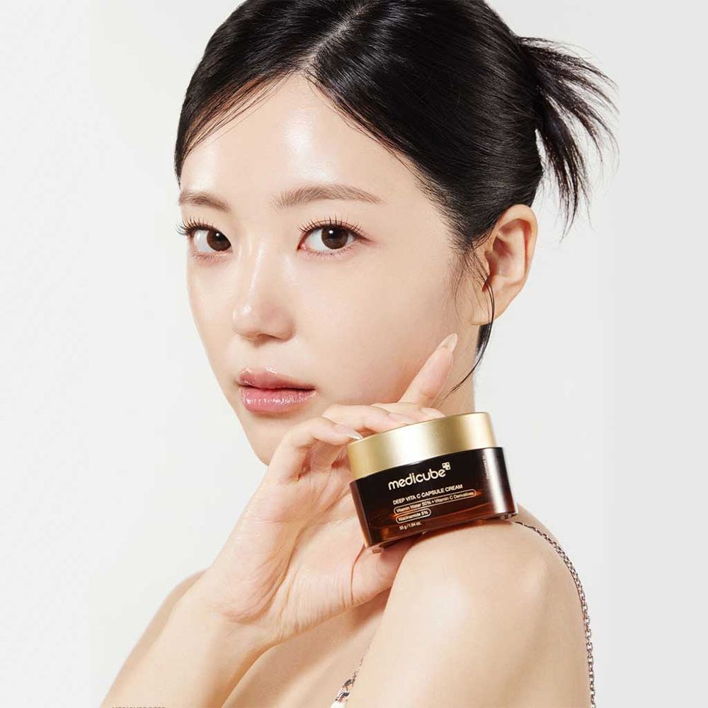Una donna tiene la Medicube Deep Vita C Capsule Cream sulla spalla.