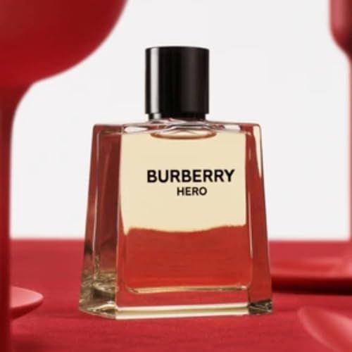 Flacone di profumo con logo "Burberry Hero". Flacone quadrato trasparente con tappo nero. Su sfondo rosso.