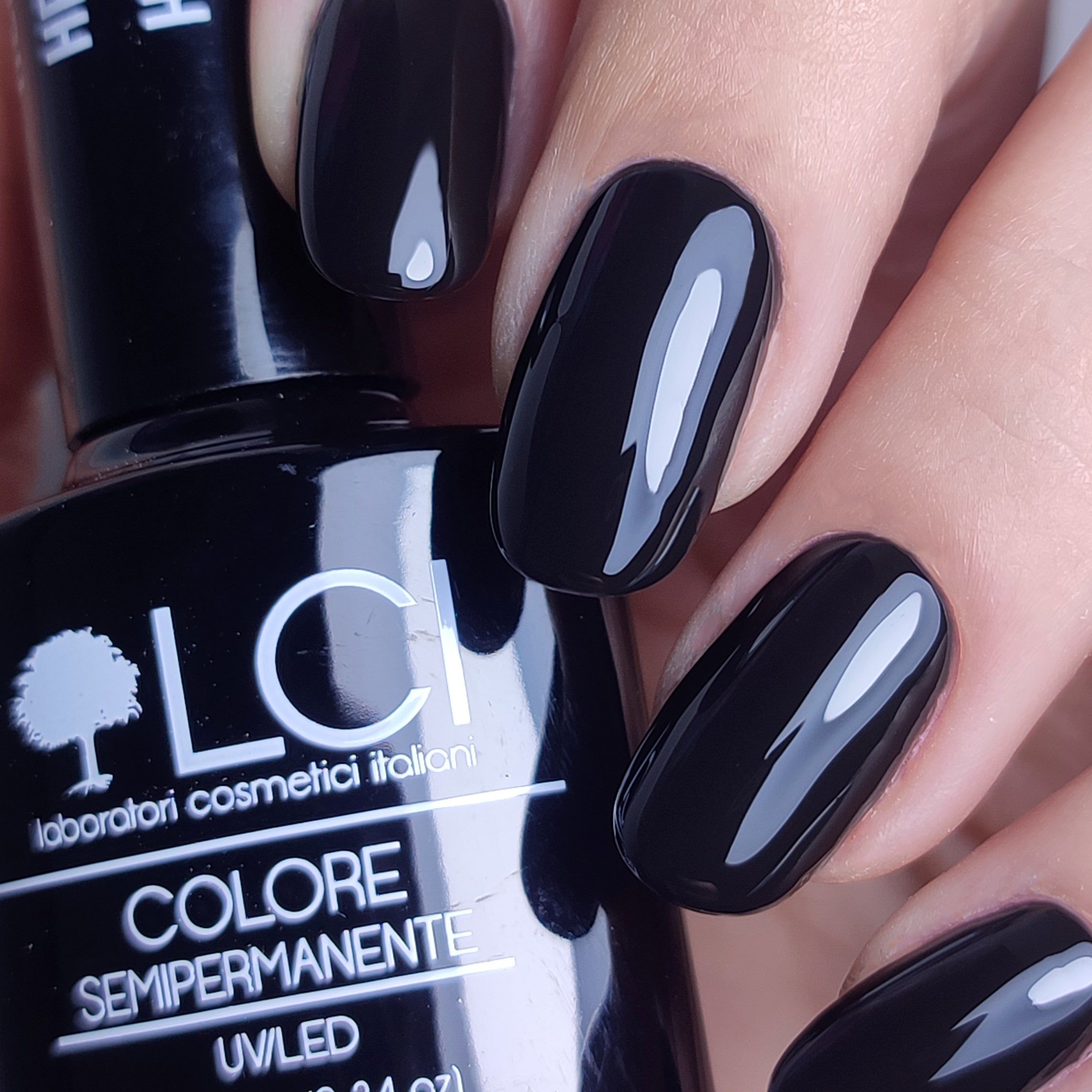 Unghie smaltate con smalto gel nero. Flacone con scritta: LCI, Colore Semipermanente, UVLED.