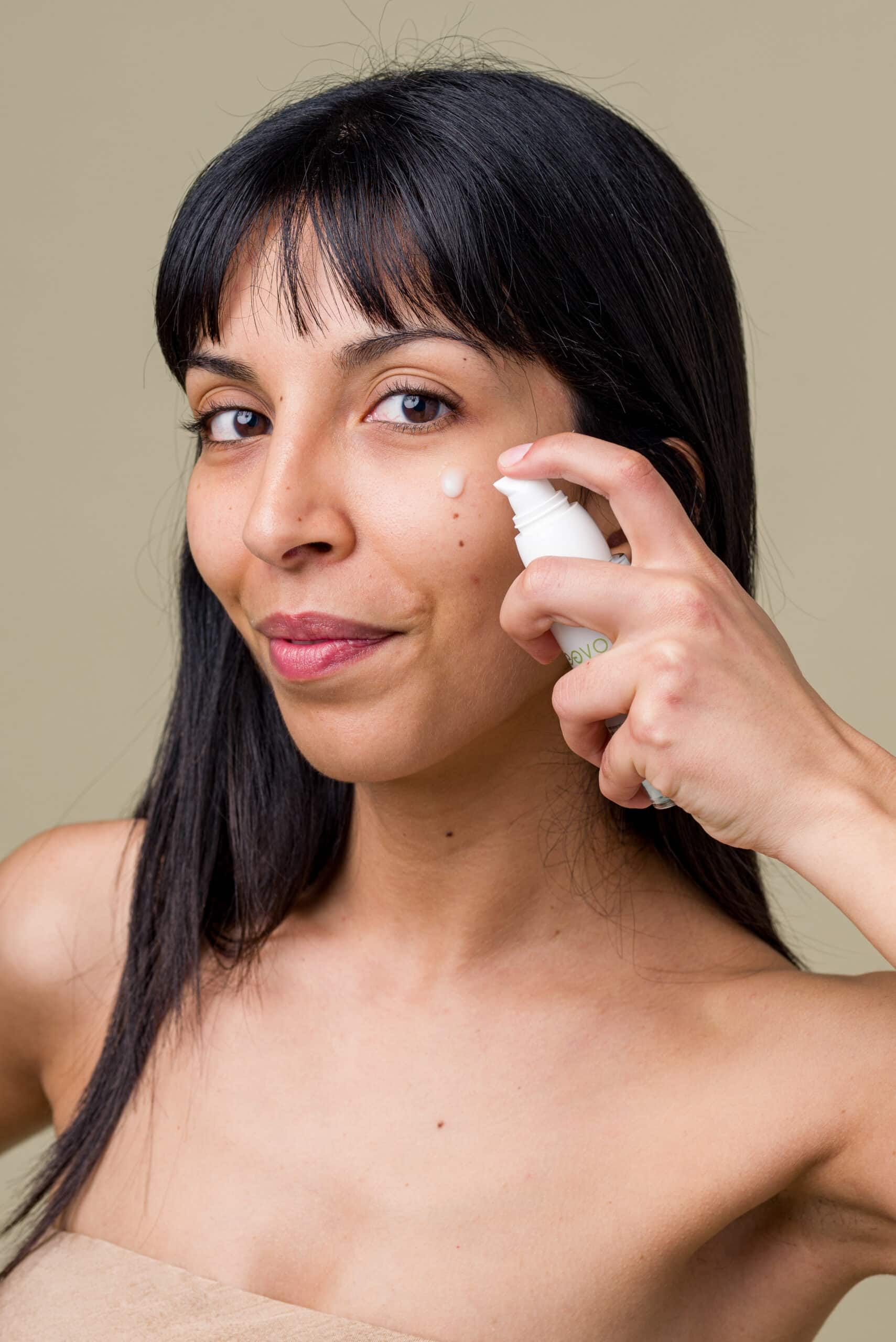 Donna applica siero. Scritta: Oleevo, Siero viso & Décolleté. Flacone bianco.