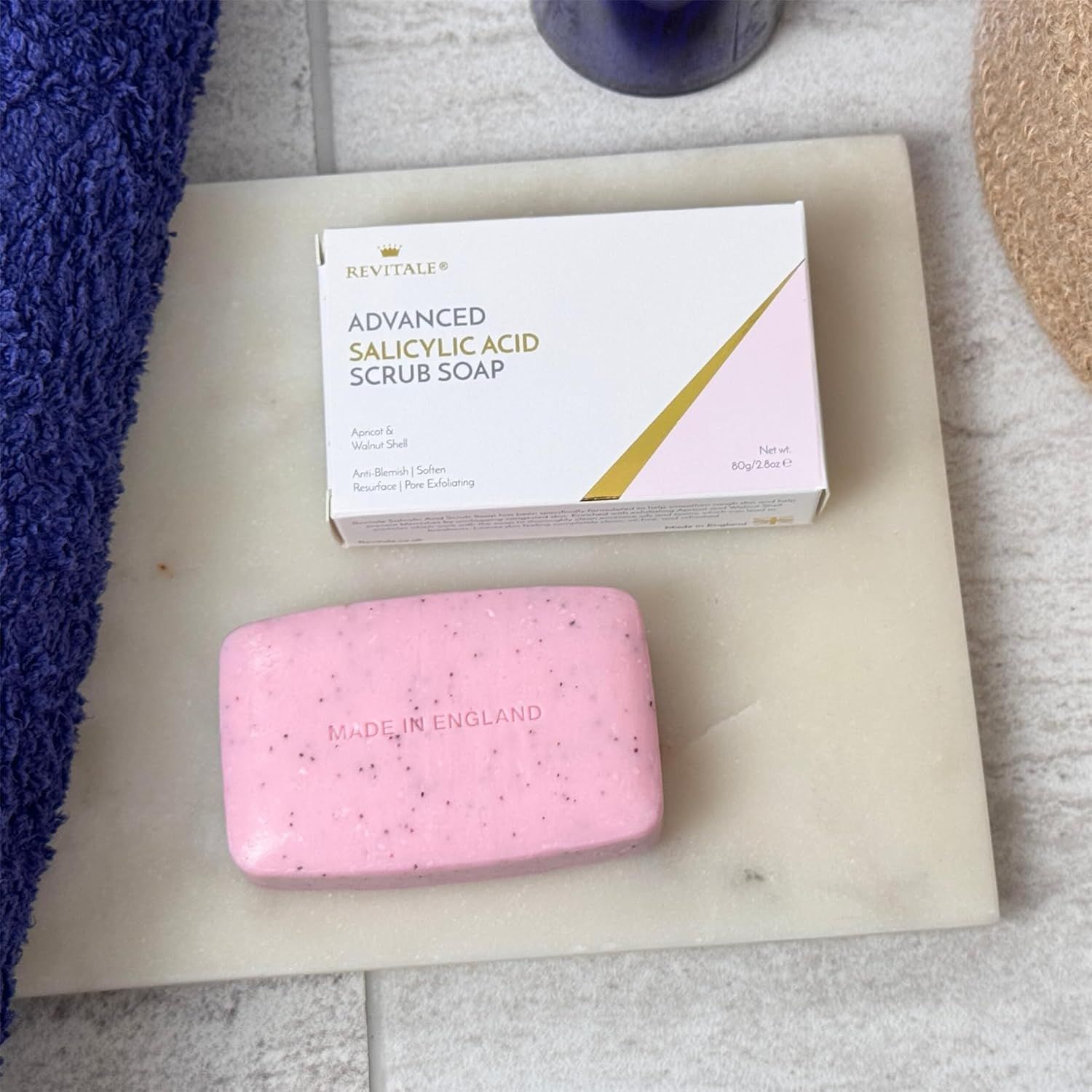 Sapone rosa con particelle nere e confezione su lastra di marmo. Sapone con 'MADE IN ENGLAND'.